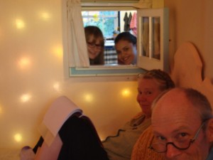 Tom and Nancy Melvin, Lazure painters in foreground in Feather Room. Farmer John’s wife Haidy (right) and Finnish friend Milla look in through a tiny window from the barn kitchen. (Window was placed there to serve breakfast in bed to Feather Room guests.)